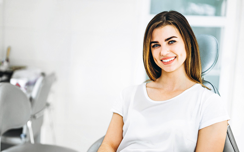 A woman in a dental office, smiling and posing for the camera.